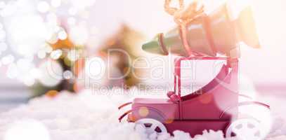 Toy car carrying christmas tree on fake snow