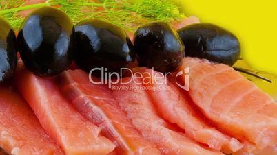 Salmon slices on a plate and black olives