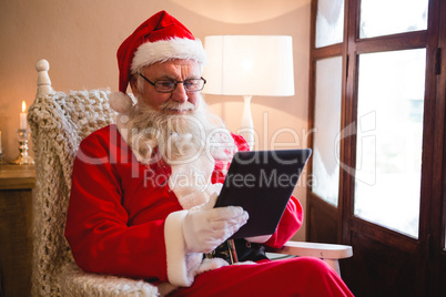 Santa claus using digital tablet in living room