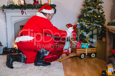 Santa Claus arranging gifts near christmas tree