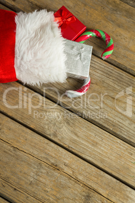 Wrapped gift box and candy cane in stocking on wooden wall