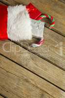 Wrapped gift box and candy cane in stocking on wooden wall