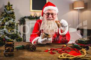 Smiling santa claus showing wooden bowl at home during christmas time