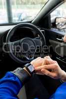 Cropped image of woman using smart watch in car