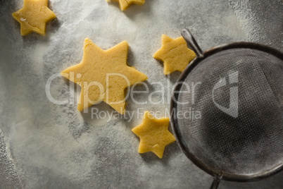 Star shape cookies on flour with strainer