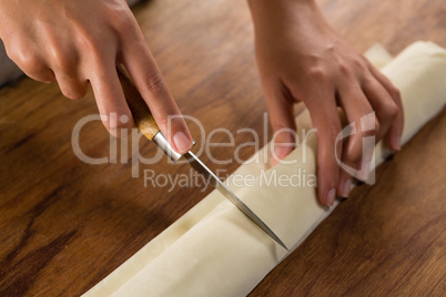 Woman slicing dough on chopping board