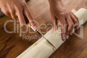 Woman slicing dough on chopping board