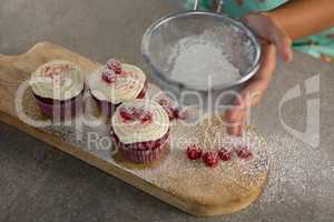 Woman staining flour on cupcakes