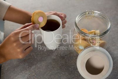 Woman dipping a cookie into black coffee