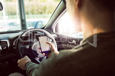 Midsection of man using smartphone in car
