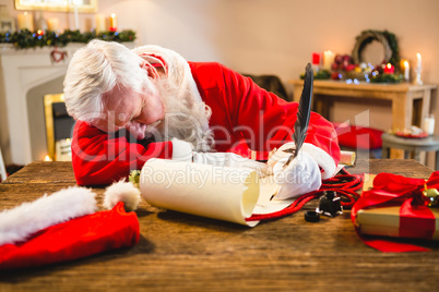 Santa claus sleeping at table while writing a letter with a quill