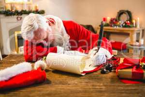 Santa claus sleeping at table while writing a letter with a quill