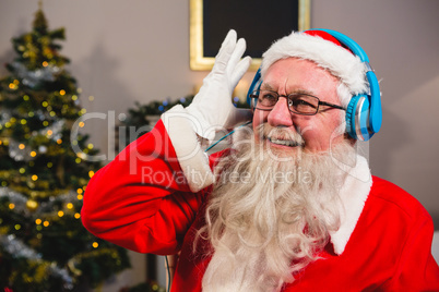 Santa claus listening to music on headphones at home