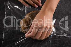Woman wrapping dough in a plastic wrap
