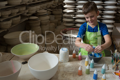 Boy painting a bowl in pottery shop