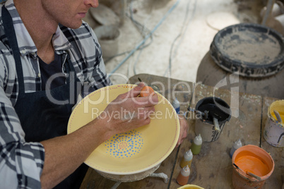Male potters painting a bowl in pottery workshop