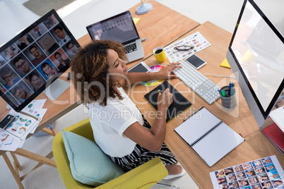 Female executive working over graphic tablet at her desk