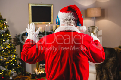 Santa claus listening to music on headphones at home during christmas time