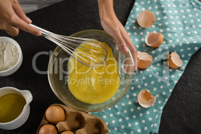 Woman beating eggs with a whisk in a bowl