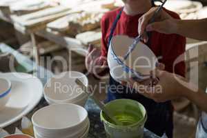 Mid section of female potter and boy painting bowl