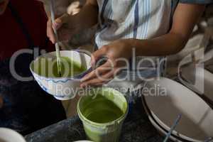 Mid section of female potter and boy painting bowl