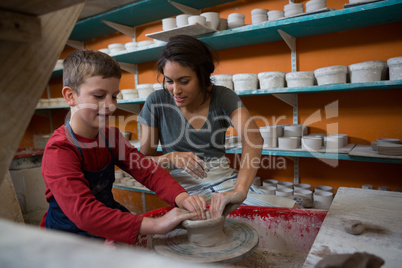 Female potter assisting boy in molding a clay