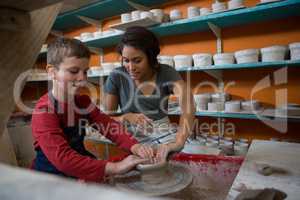 Female potter assisting boy in molding a clay