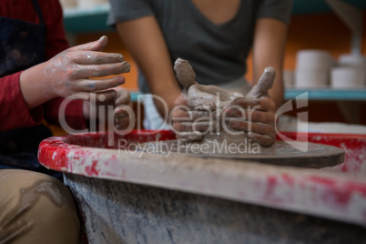 Female potter assisting boy in molding a clay