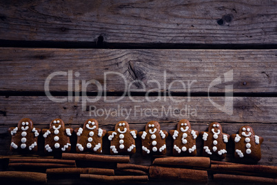 Gingerbread cookies and cinnamon sticks arranged on wooden plank