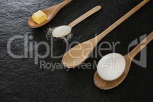 Wooden spoons with egg, cheese cube and powdered sugar