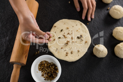 Woman adding dry fruits over flattened dough