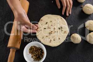 Woman adding dry fruits over flattened dough