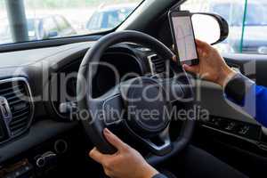 Cropped image of woman using phone during test drive