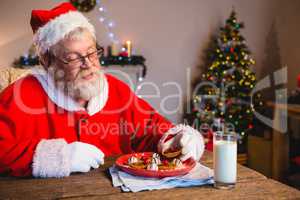 Santa Claus having cookie with a glass of milk