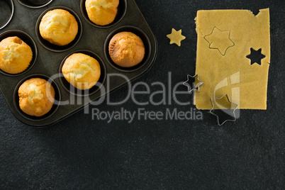 Plain cupcakes in baking tray with star shape dough and cutter