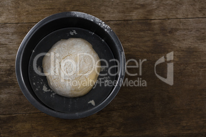 Kneaded dough placed in a bowl on a wooden table