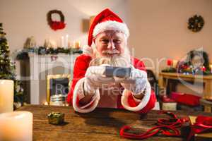 Portrait of santa claus showing gift box in living room at home