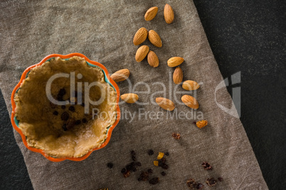 Raisin being stuffed in tart with almond on wax paper