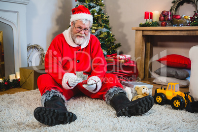 Santa claus sitting on the floor and counting cash at home