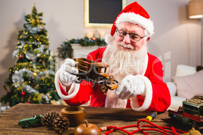 Smiling santa claus looking at toy car in living room