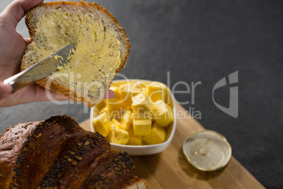 Woman applying butter over multigrain bread slice
