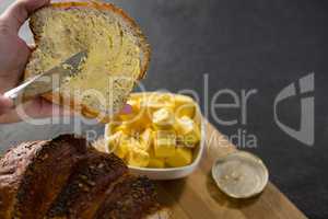 Woman applying butter over multigrain bread slice