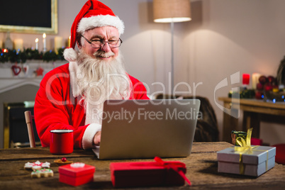 Santa Claus using laptop on table