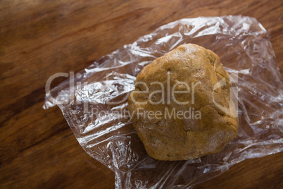 Dough placed over plastic wrap on a wooden table