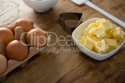 Eggs, butter cubes, whisk and cookie cutter on a wooden table
