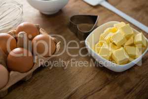 Eggs, butter cubes, whisk and cookie cutter on a wooden table