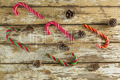 Candy canes and pine cones on wooden plank
