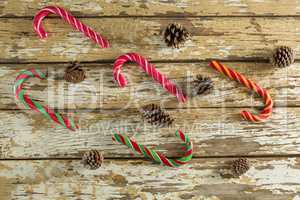Candy canes and pine cones on wooden plank