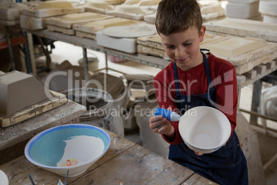 Boy decorating bowl with water color