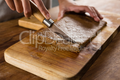 Woman slicing dough on chopping board